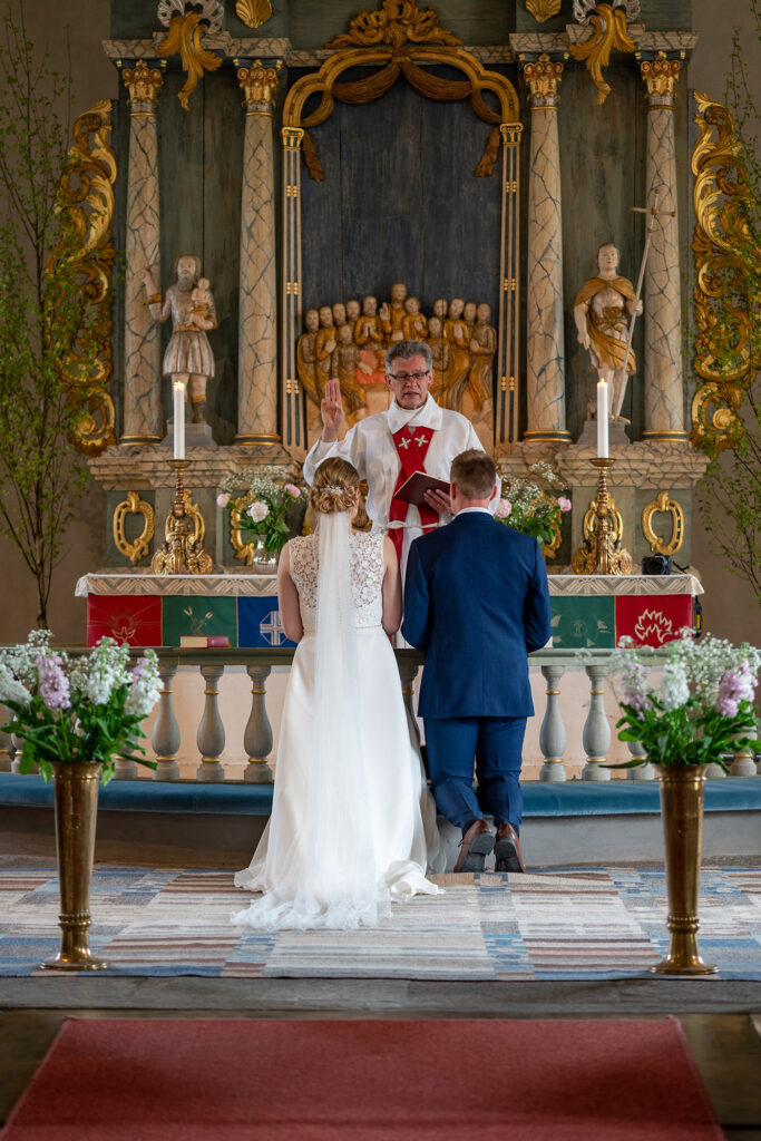 Bröllopspar på knä framför prästen i Karlanda kyrka Årjäng