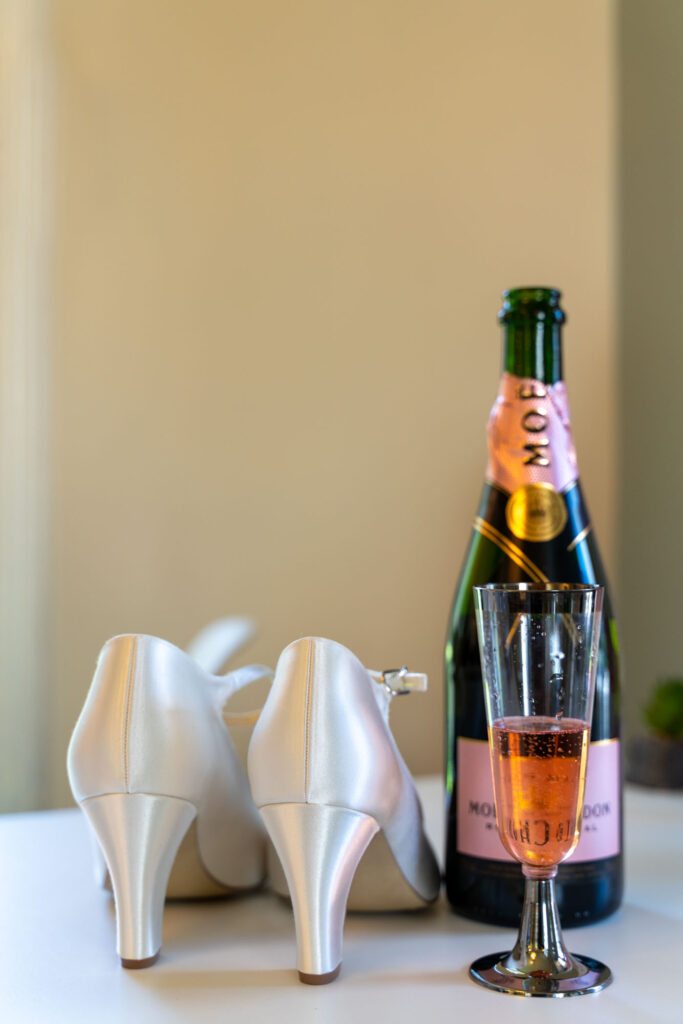 Brudens skor och champagneflaska på ett bord.