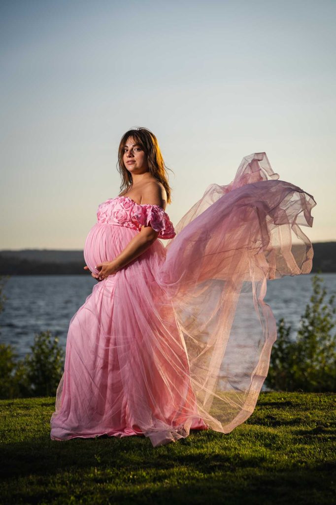 Gravid kvinna med rosa kjol som lyfter i vinden.