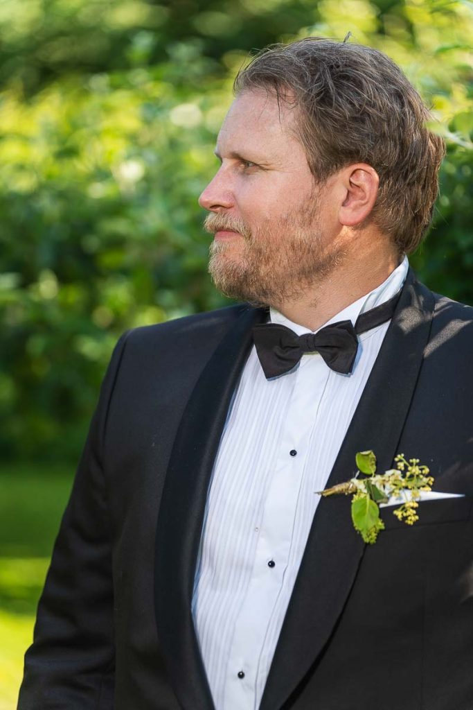 Porträtt av brudgummen i trädgården omgiven av fruktträd.