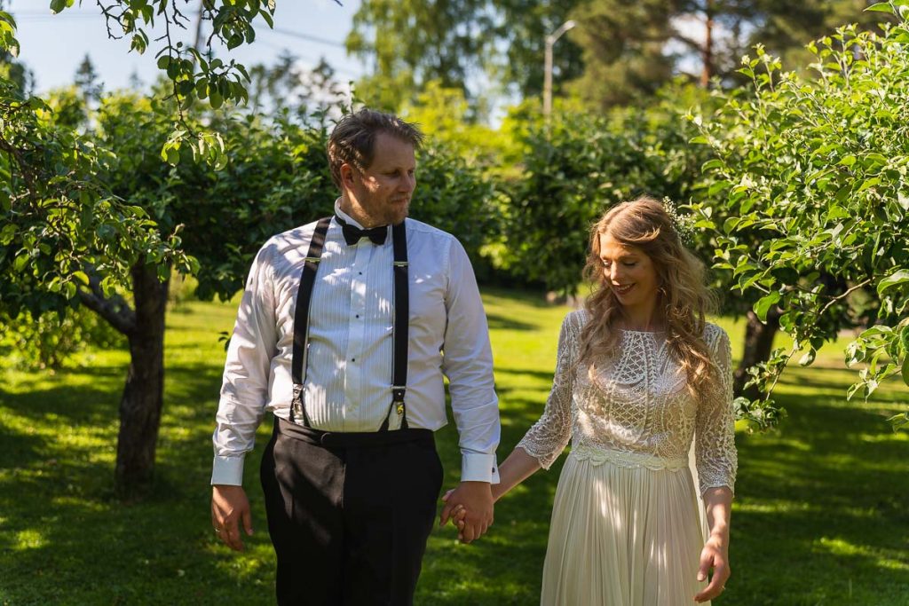 Brudparet vandrar hand i hand genom trädgården.