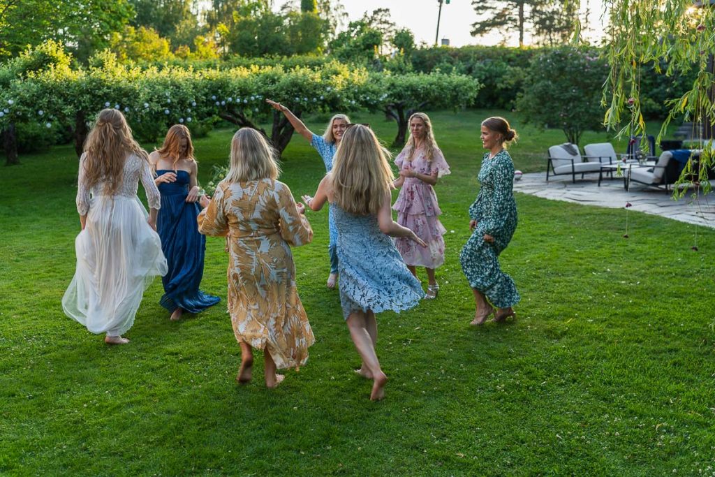 Bruden med vänner dansar i trädgården.