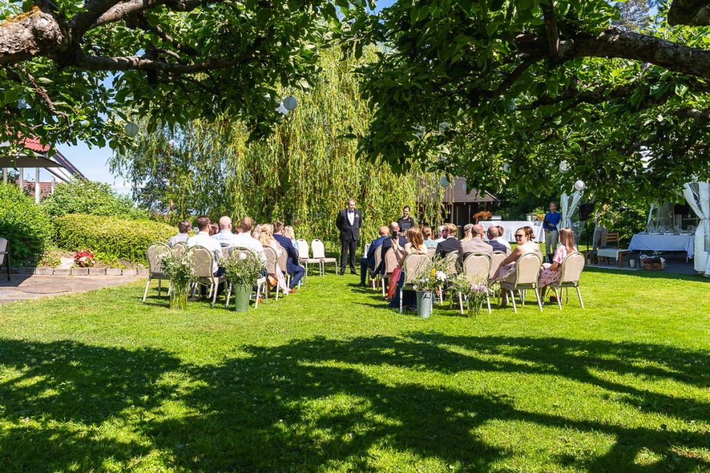 Alla gäster är samlade i trädgården för bröllop och brudgummen står i mitten och väntar på bruden.