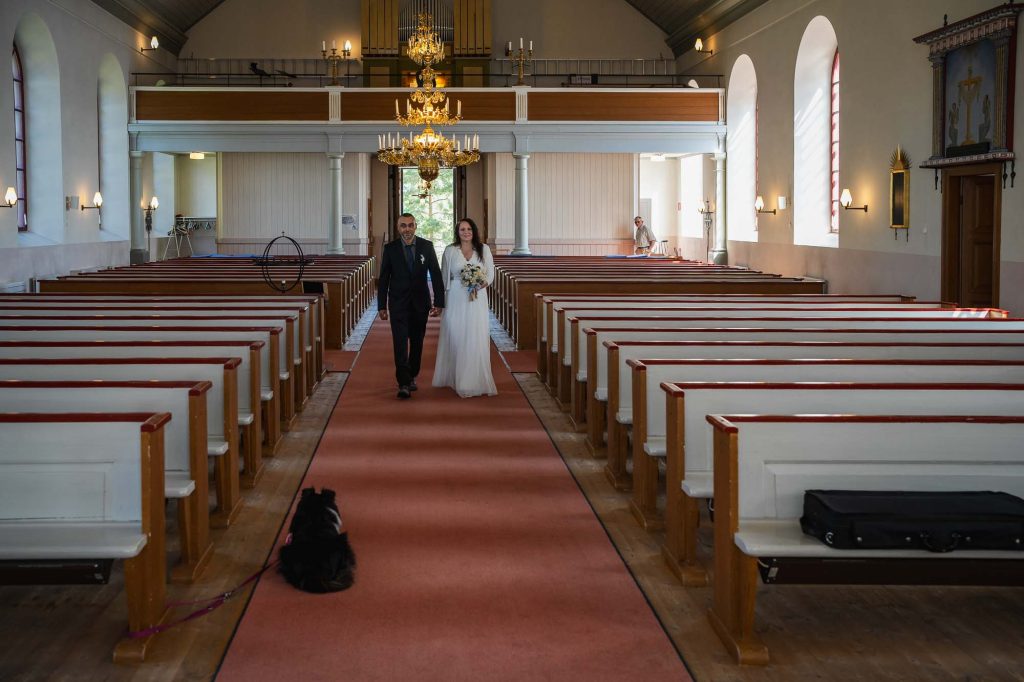 Bröllopsparet går arm I arm mot altaret I västra Fågelviks kyrka i Töcksfors.