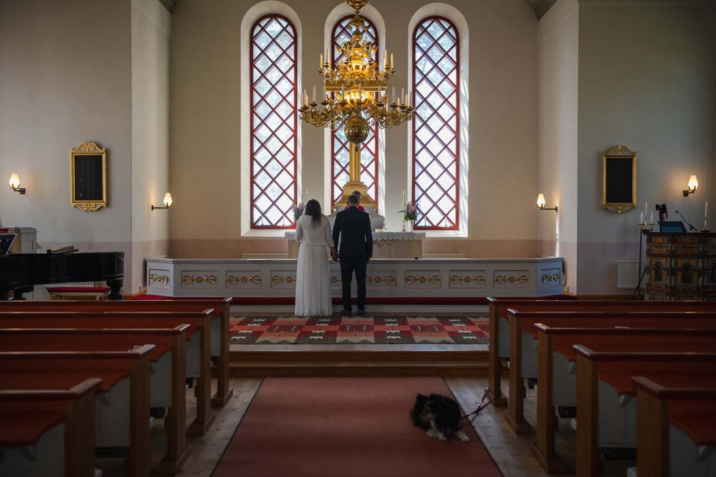 Brudparet står framför altaret i västra Fågelviks kyrka i Töcksfors.