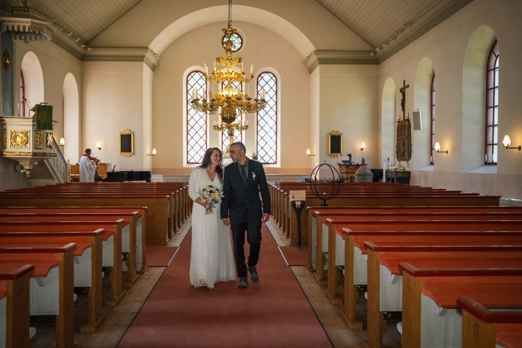 Brudparet går hand i hand ut ur västra Fågelviks kyrka i Töcksfors.