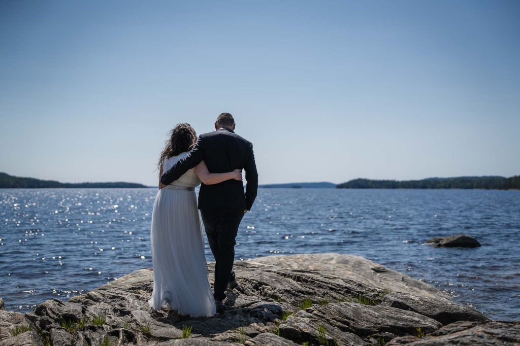 Brudparet håller om varandra och går mot sjön Foxen utanför västra Fågelviks kyrka.