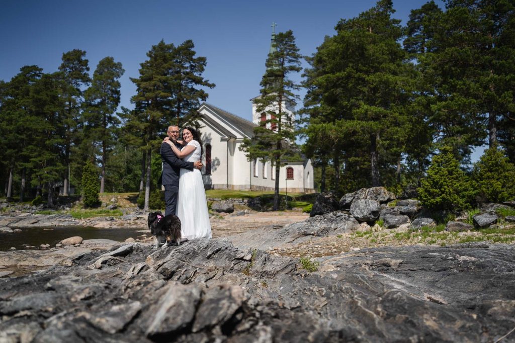 Brudparet håller om varandra utanför västra Fågelviks kyrka.