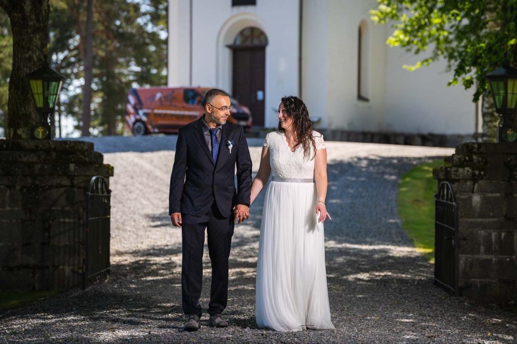 Brudparet går nedför gången till västra Fågelviks kyrka.